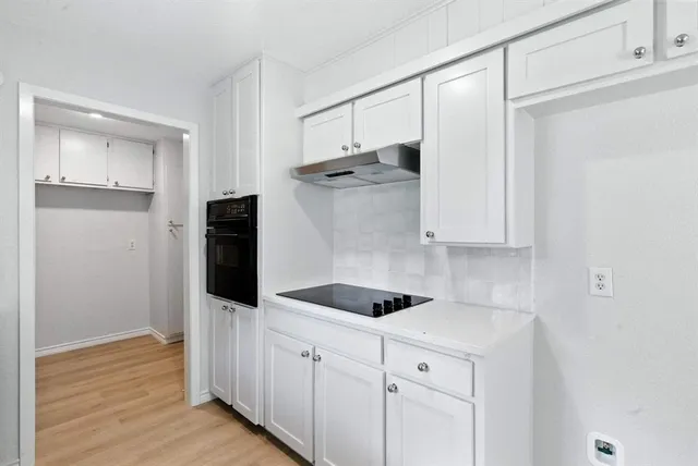 a kitchen with white cabinets and refrigerator