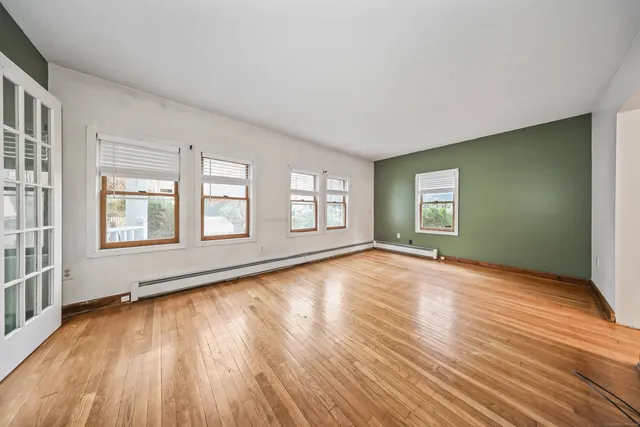 an empty room with wooden floor and windows