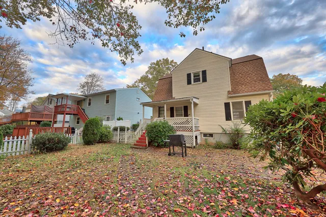 a backyard of a white house with potted plants and a large tree