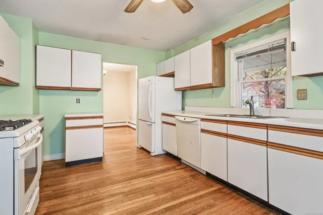 a kitchen with a sink cabinets stainless steel appliances and wooden floor