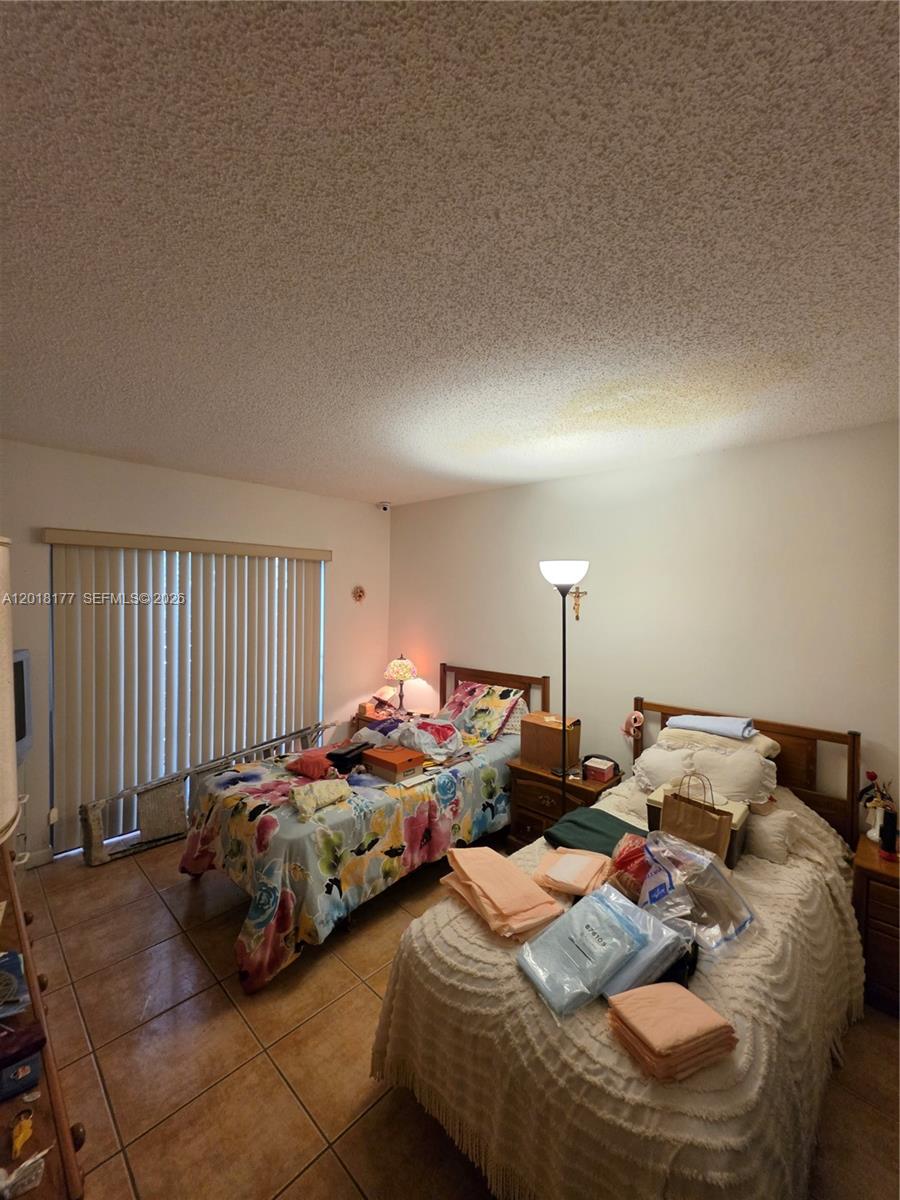 10908 Southwest 72nd Street, Unit 215 Miami, FL 33173 - Photo 8 of 25 a bedroom with two beds and a chair