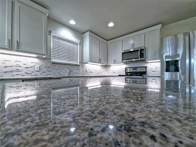 a kitchen with granite countertop a stove a sink and a microwave