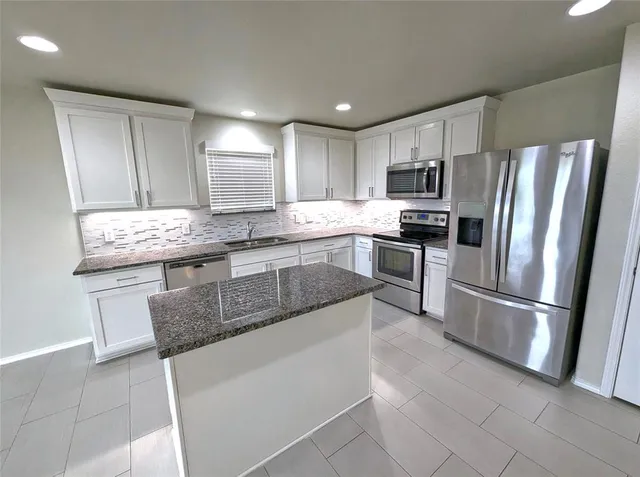 a kitchen with stainless steel appliances granite countertop a sink stove refrigerator and cabinets