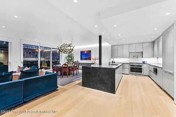 a kitchen with stainless steel appliances kitchen island granite countertop a refrigerator a stove top oven and a dining table with wooden floor