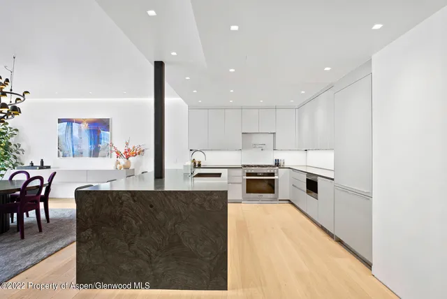 a large white kitchen with living room a stove a couch with wooden floor