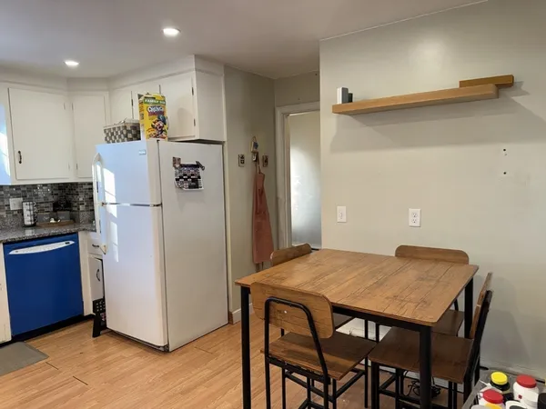 a kitchen with refrigerator and wooden floor