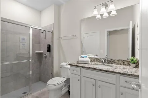 a bathroom with a granite countertop sink a toilet and shower