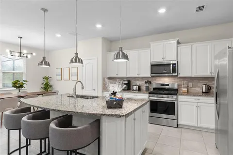 a kitchen with stainless steel appliances granite countertop a sink a stove and chairs