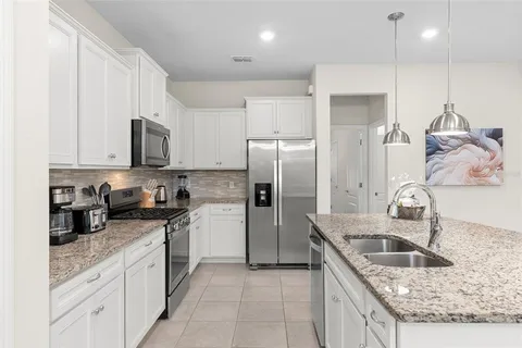 a kitchen with stainless steel appliances granite countertop a sink a refrigerator and a granite counter tops