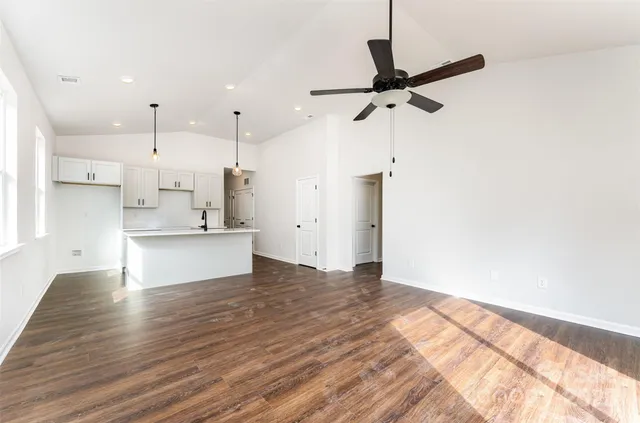 a view of kitchen and empty room with wooden floor