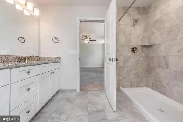 a bathroom with a granite countertop sink a mirror a bathtub and shower