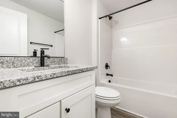 a bathroom with a granite countertop sink toilet and shower