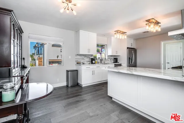 a kitchen with stainless steel appliances a white cabinets and wooden floors