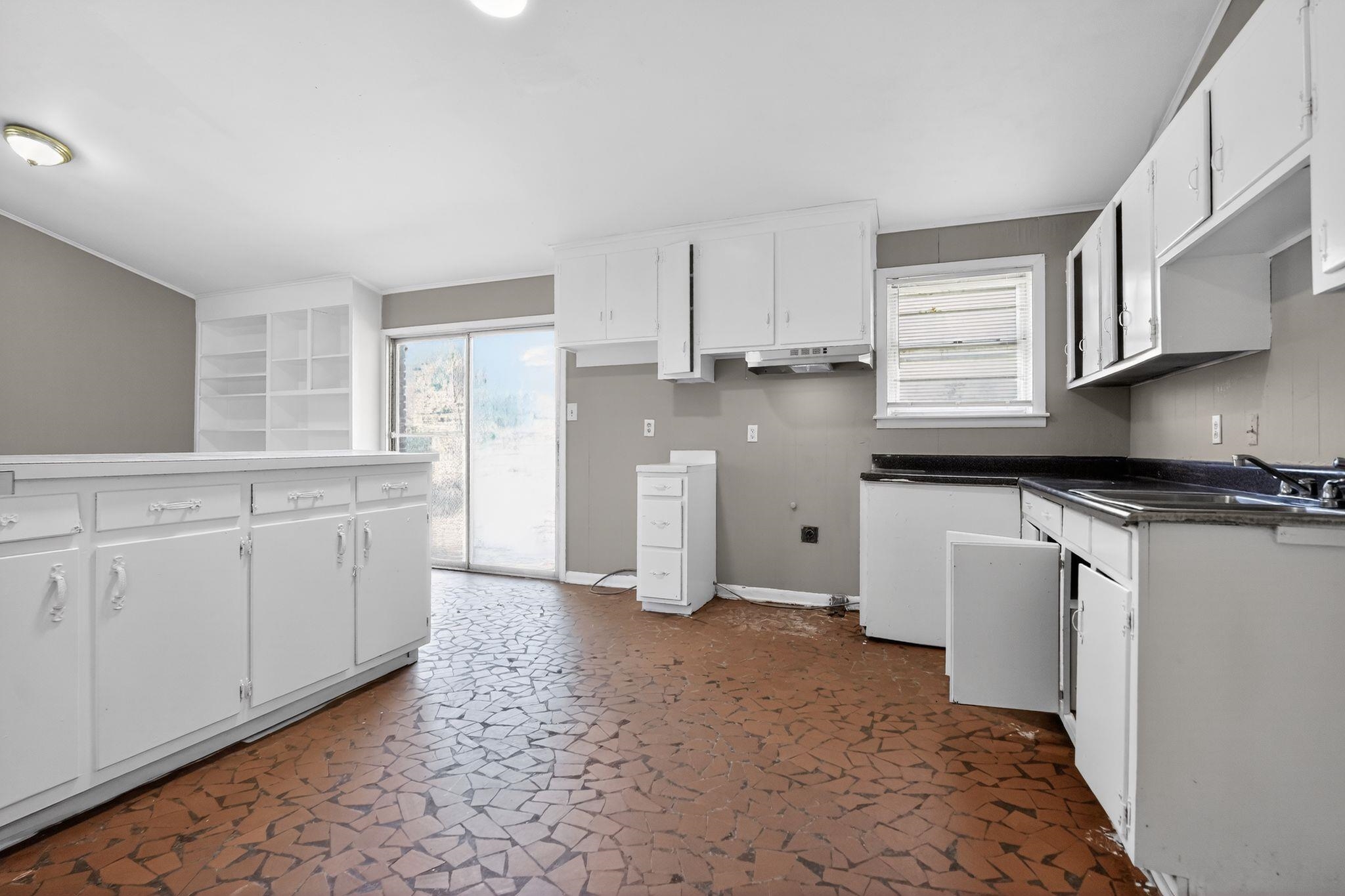3445 Powers Road Memphis, TN 38128 - Photo 22 of 35 Kitchen featuring white cabinetry, dark countertops, a built-in shelving unit, and sliding glass doors