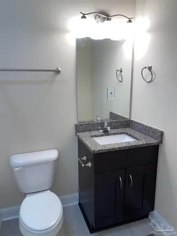 a bathroom with a granite countertop toilet sink and mirror