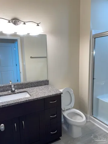 a bathroom with a granite countertop toilet sink and mirror