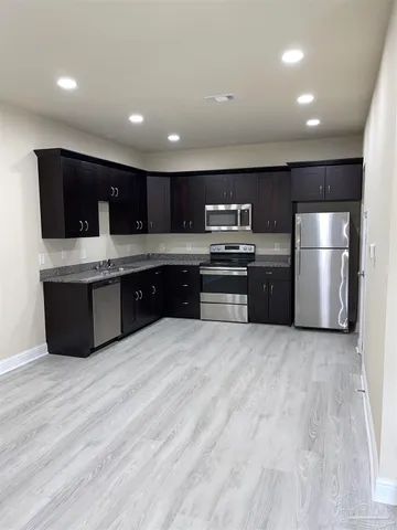 a large kitchen with stainless steel appliances granite countertop a stove and a refrigerator