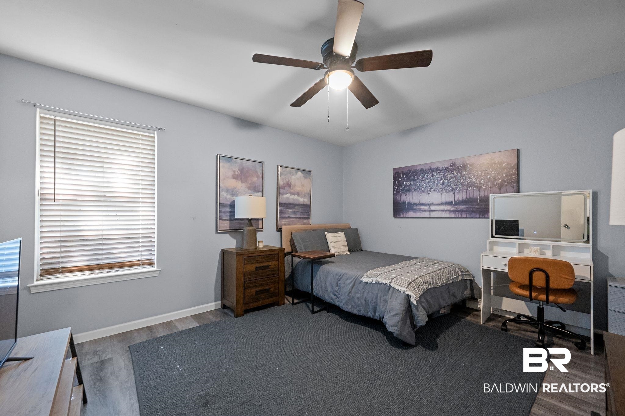 4724 Wicker Way Mobile, AL 36609 - Photo 26 of 36 Recessed lighting, a ceiling fan fixture, and a large window with horizontal blinds illuminate this room, featuring wood-finish flooring and a neutral wall color