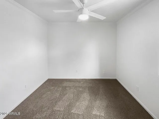 an empty room with a fan & a window