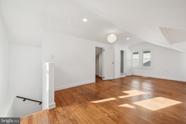 a view of an empty room with wooden floor and windows