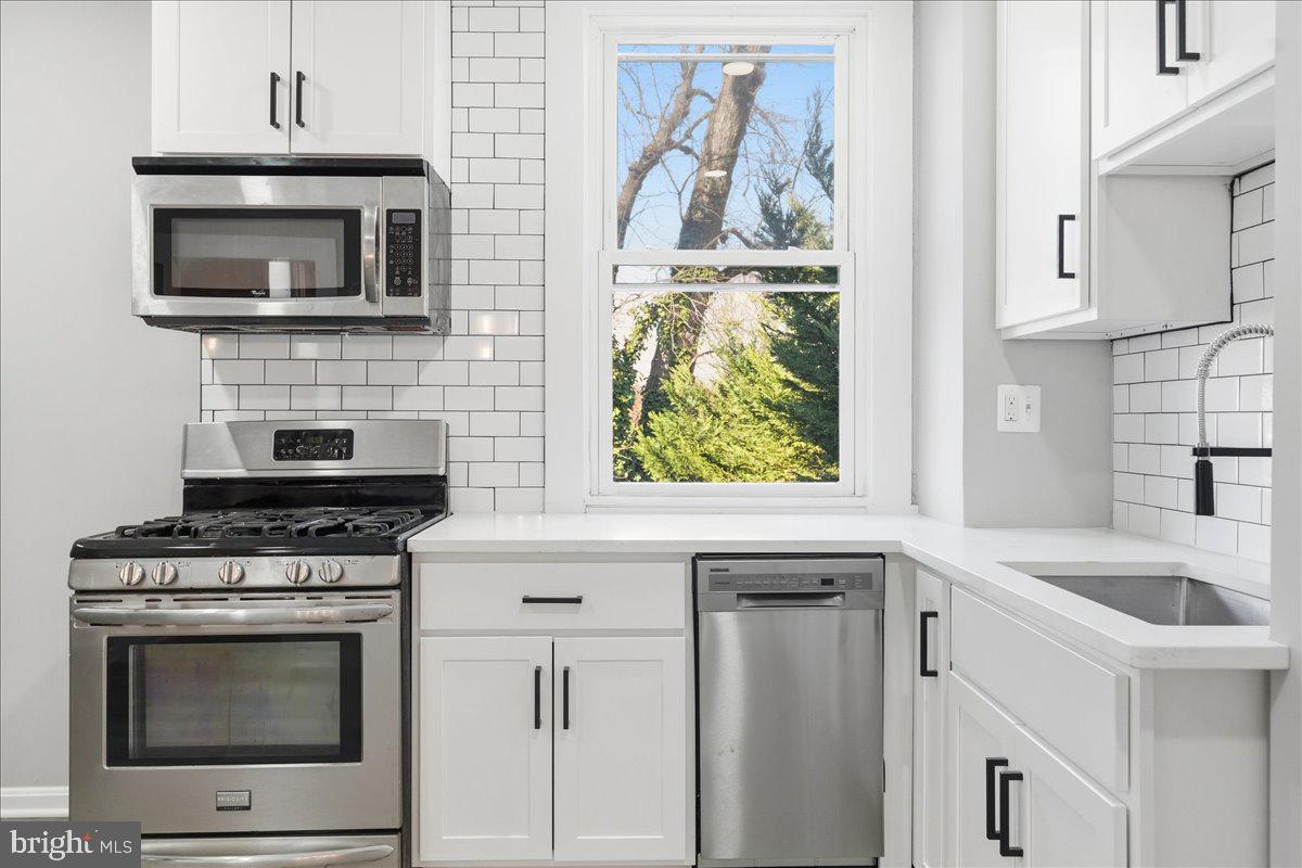 3414 Harford Road Baltimore, MD 21218 - Photo 12 of 32 a kitchen with granite countertop a stove top oven microwave and cabinets