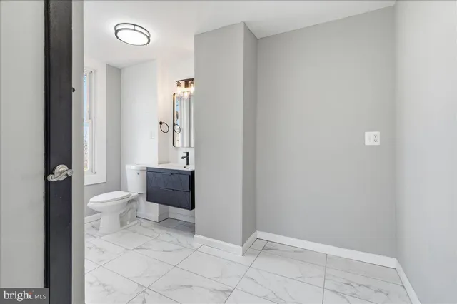 a bathroom with a granite countertop toilet and a sink