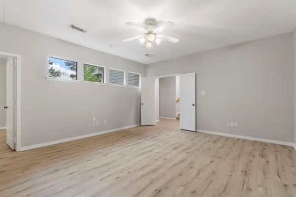 an empty room with wooden floor and windows