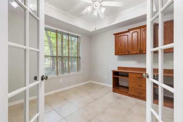 a room with chandelier fan and windows
