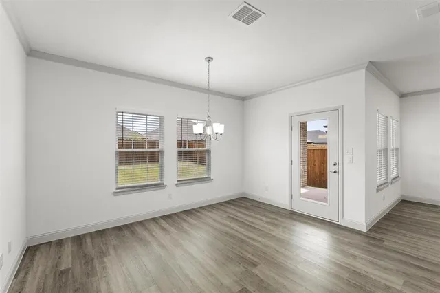 an empty room with wooden floor cabinet and windows
