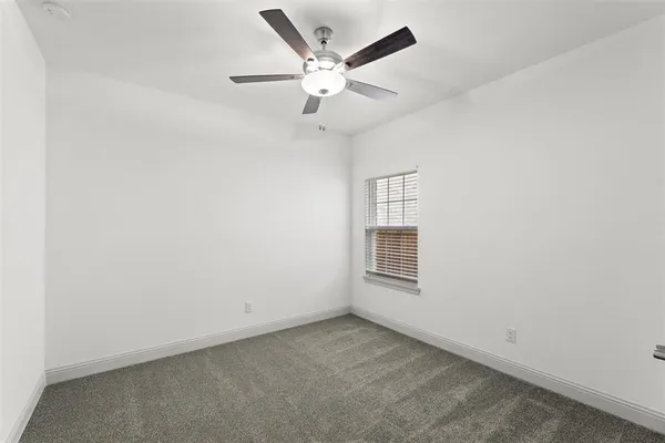 an empty room with a window and a ceiling fan