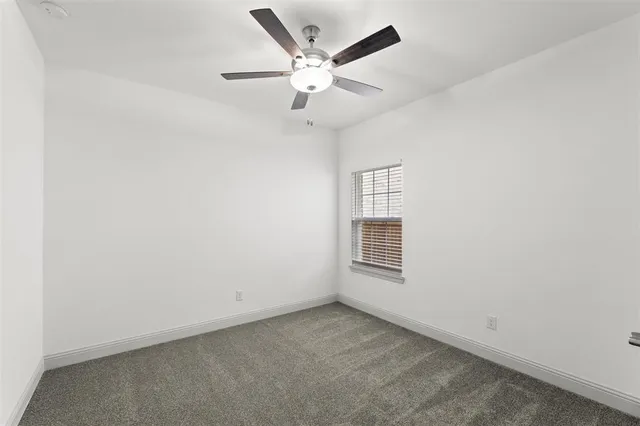 an empty room with a window and a ceiling fan