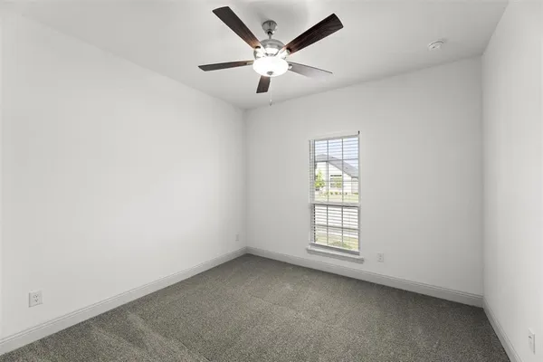 an empty room with ceiling fan and window