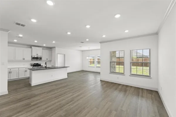 a large kitchen with stainless steel appliances granite countertop a large counter top a stove and a wooden floors