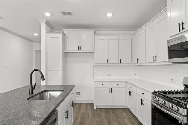 a kitchen with granite countertop a sink stainless steel appliances and cabinets
