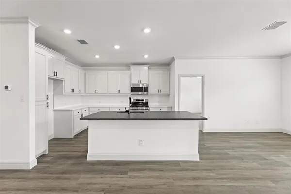 a kitchen with stainless steel appliances granite countertop a sink a stove a refrigerator and white cabinets