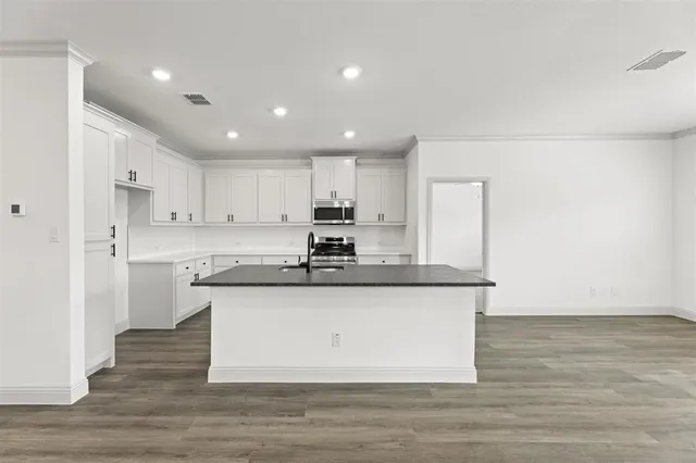 a kitchen with stainless steel appliances granite countertop a sink a stove a refrigerator and white cabinets