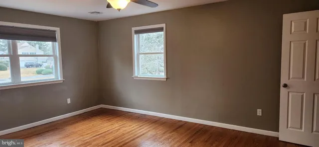 a view of an empty room with window and wooden floor