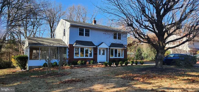 a view of a white house with a large tree and yard