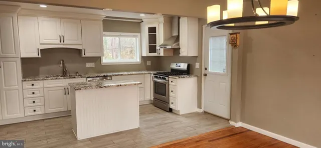 a kitchen with white cabinets a sink dishwasher and a stove with wooden floor