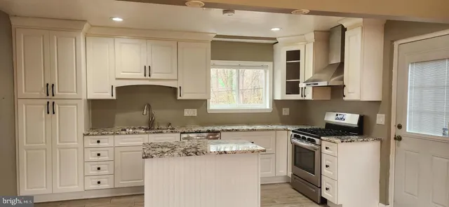 a kitchen with kitchen island granite countertop a sink cabinets and stainless steel appliances