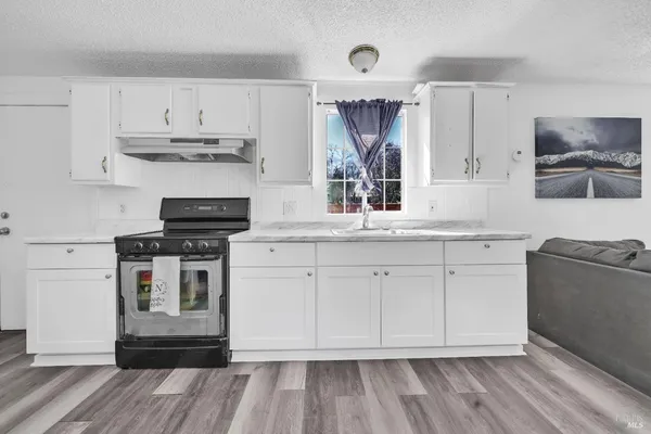 a kitchen with stainless steel appliances white cabinets a sink and a stove