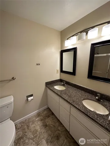 a bathroom with a granite countertop sink a toilet and mirror