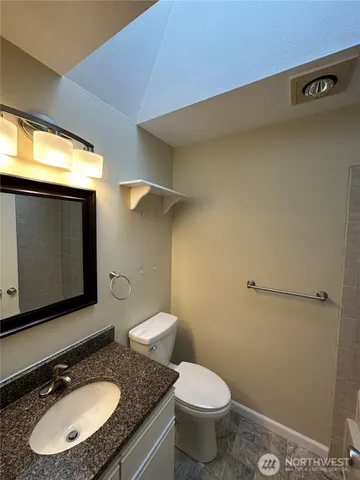 a bathroom with a granite countertop sink toilet and mirror