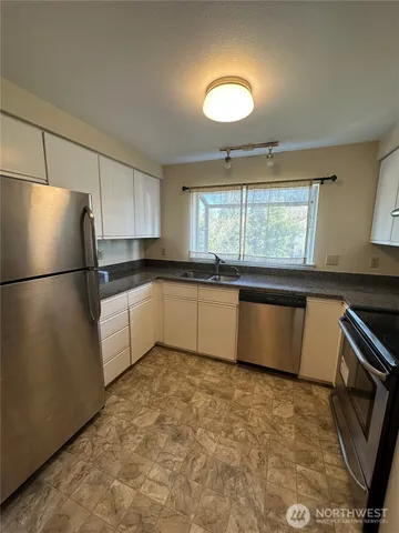 a kitchen with granite countertop a sink stainless steel appliances and cabinets