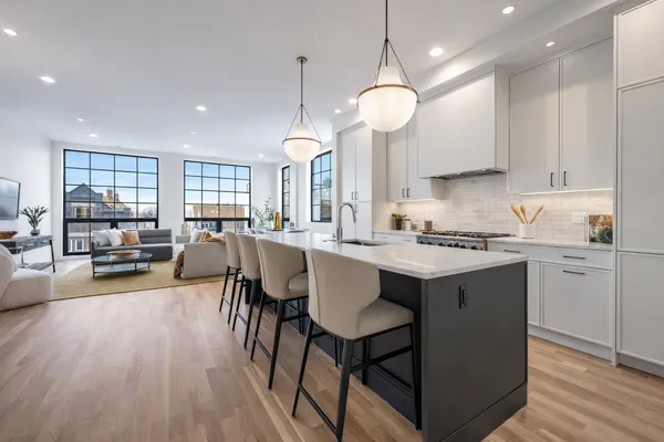 a kitchen with granite countertop a stove a sink a dining table and chairs with wooden floor
