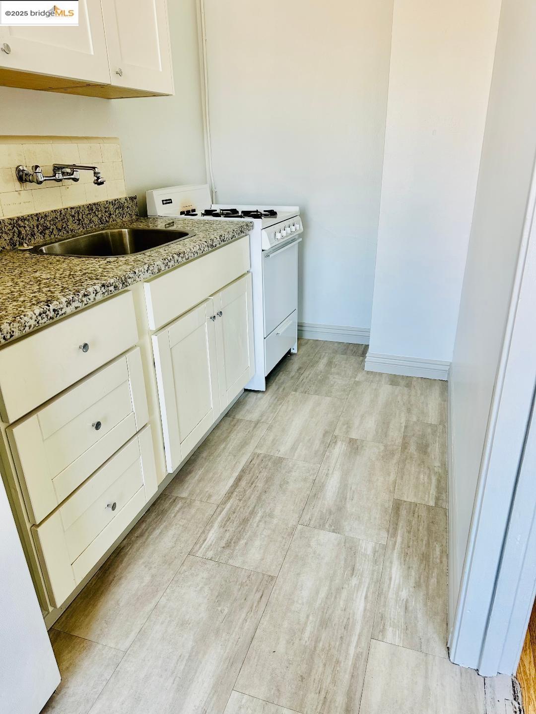 2240 MacArthur Boulevard Oakland, CA 94602 - Photo 9 of 13 Kitchen with white range with gas cooktop, light wood-style flooring, backsplash, and white cabinetry