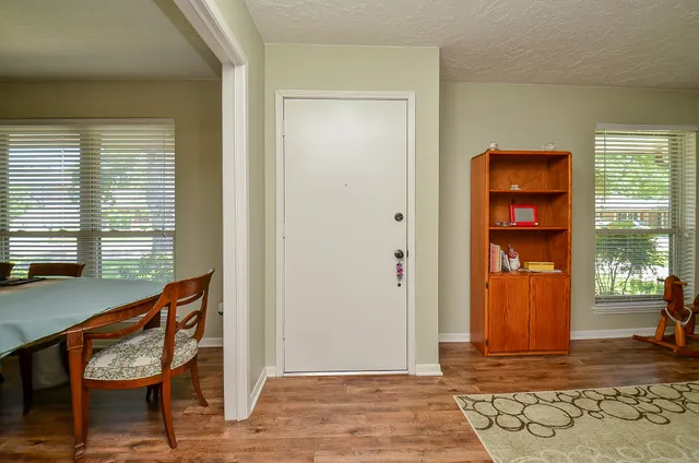 a living room with chair and two windows