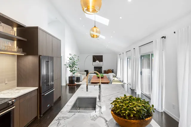 a living room with stainless steel appliances furniture a rug and a kitchen view