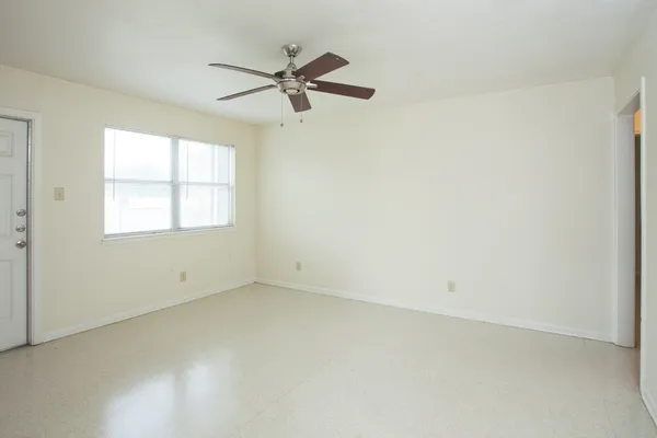 an empty room with a window and a fan