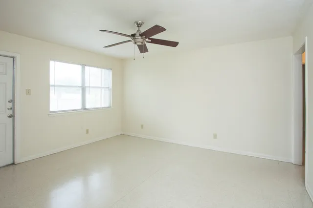 an empty room with a window and a fan